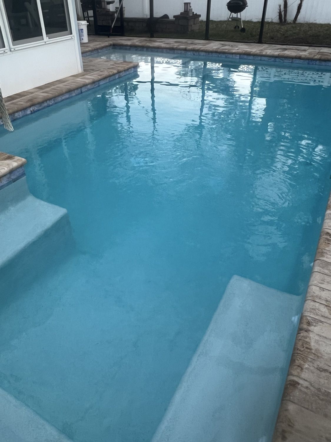 Clean residential pool with clear water beside a covered patio