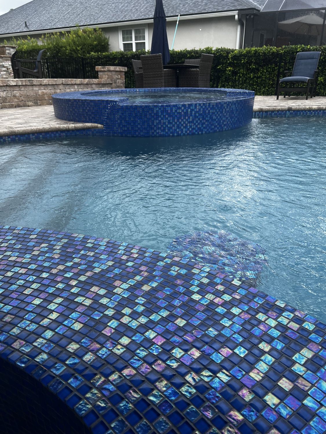 Clean iridescent blue mosaic tile surrounding pool and spa