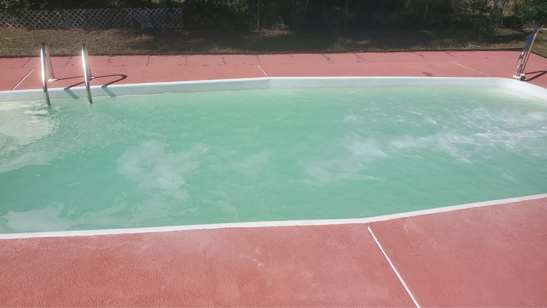 Same rectangular pool with cloudy light green water during treatment